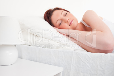 Beautiful red-haired female sleeping in her bed