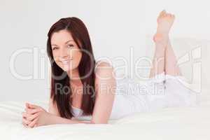 Beautiful red-haired female having a rest while lying on her bed