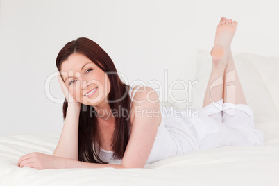 Attractive red-haired female having a rest while lying on her be