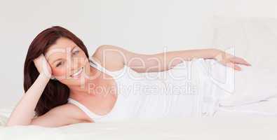 Pretty red-haired female having a rest while lying on her bed