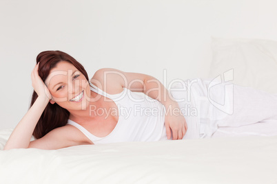 Gorgeous red-haired female having a rest while lying on her bed