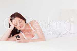 Beautiful red-haired female relaxing with her mobile while lying