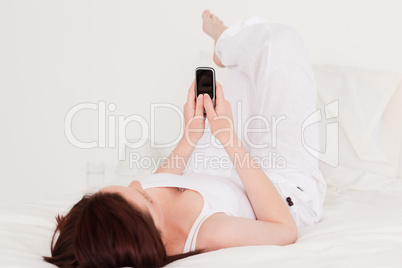 Pretty red-haired female relaxing with her mobile while lying on