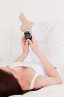 Gorgeous red-haired female relaxing with her mobile while lying