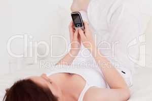 Charming red-haired female relaxing with her mobile while lying