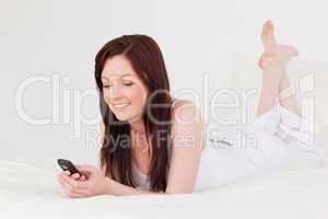 Good looking red-haired female writing a text on her mobile whil