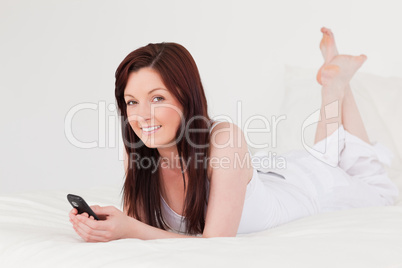 Attractive red-haired female writing a text on her mobile while