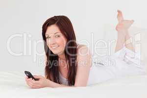 Attractive red-haired female writing a text on her mobile while