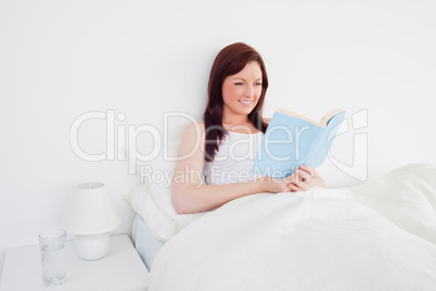 Beautiful red-haired woman reading a book while sitting on her b