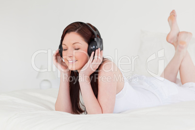 Good looking red-haired female relaxing with her headphones whil