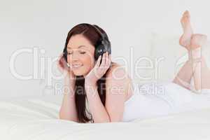 Good looking red-haired female relaxing with her headphones whil