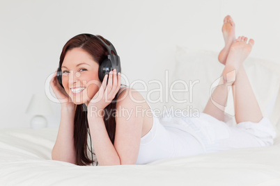 Attractive red-haired female relaxing with her headphones while