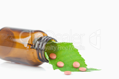 Leaf and pills in a small bottle