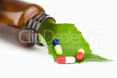 Leaf and pills in a small bottle