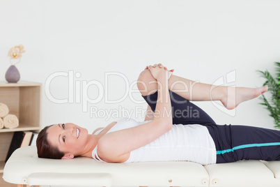 Athletic woman stretching her leg while looking at the camera