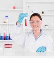 Portrait of a young scientist showing a test tube looking at the