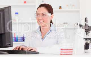 Cute scientist typing a report with her computer