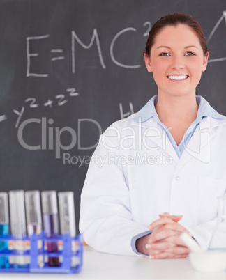 Smilling scientist stanting in front of a blackboard