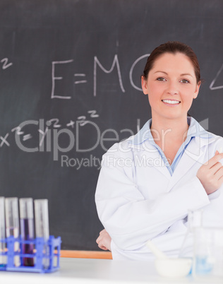 Smilling scientist stanting in front of a blackboard looking at