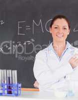 Smilling scientist stanting in front of a blackboard looking at