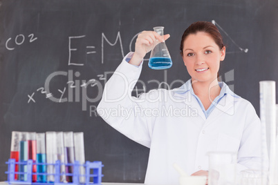 Cute scientist showing a container filled up with a blue liquid