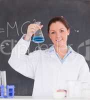 Beautiful scientist showing a container filled up with a blue li