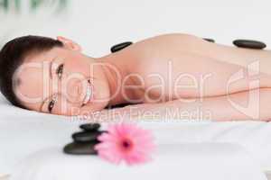 Happy young woman with massage stones and a pink gerbera