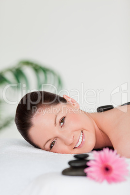 Portrait of a young woman with massage stones and a pink gerbera