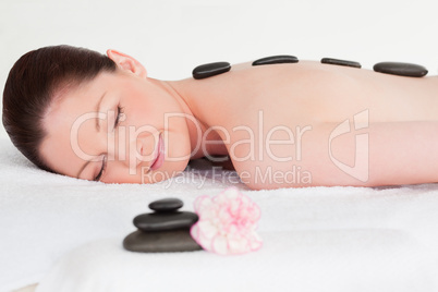 Happy young woman receiving black hot stone massage