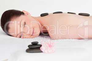 Happy young woman receiving black hot stone massage