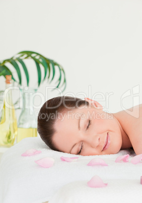 Portrait of a young woman lying on a massage table with petals