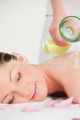 Portrait of a young female having massage oil versed on her back