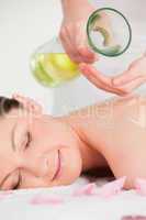 Portrait of a happy woman having massage oil versed on her back