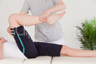 Masseuse stretching the right leg of a young woman