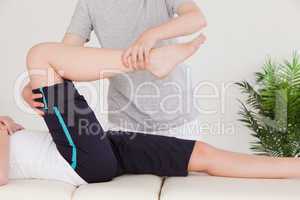 Masseuse stretching the right leg of a young woman