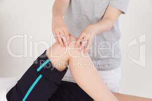 Close up of a masseuse massing the knee of an athletic woman