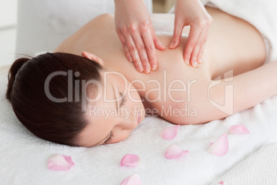 Beautiful woman having a back massage surrounded by petals