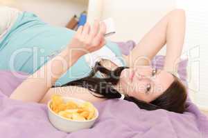 Young student lying on bed eat chips