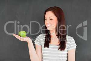 Young woman looking at the apple on her palm