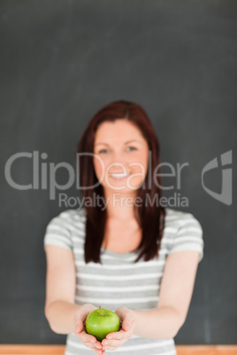 Portrait of a happy young woman showing an apple against a black