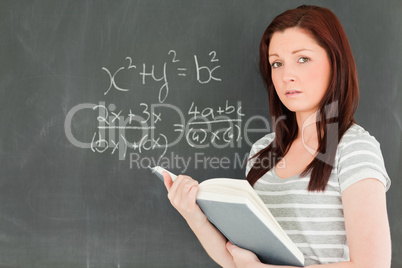 Cute woman trying to solve a mathematical equation on a blackboa