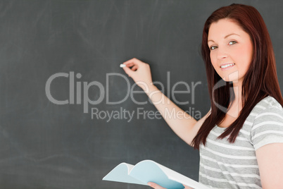 Happy young woman writting on a blackboard