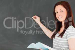 Happy young woman writting on a blackboard