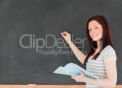 Young woman about to write on a blackboard looking at the camera
