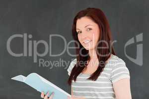 Cute woman reading her notes in front of a blackboard