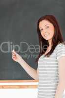 Portrait of a young woman in front of a blackboard holding a pie