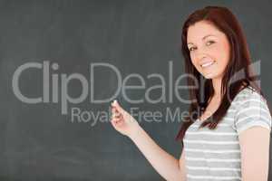 Close up of a young woman in front of a blackboard holding a pie