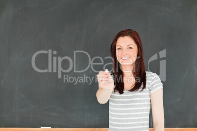 Young woman stretching a piece of chalk while standing in front