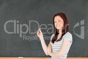 Young woman holding a piece of chalk while standing in front of