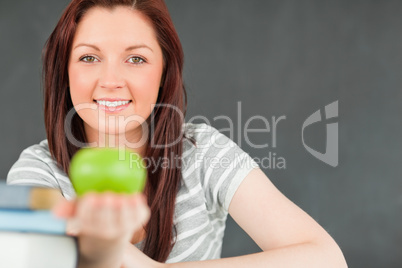 Beautilful young woman showing an apple with the camera focus on